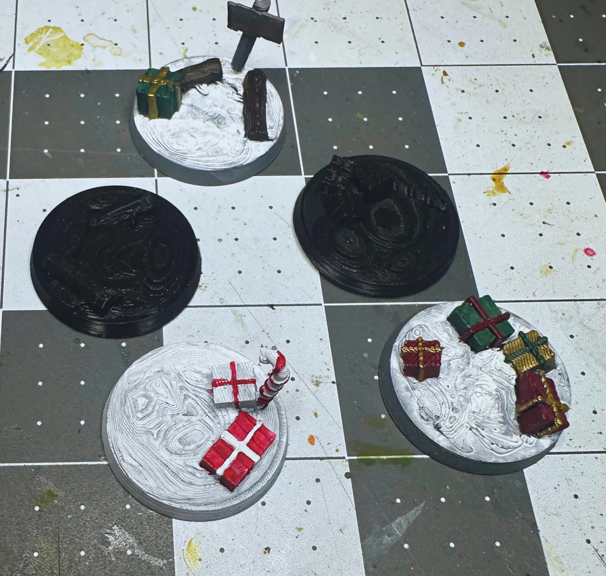 Five 28mm Christmas themed miniature bases with painted presents and snow effects
