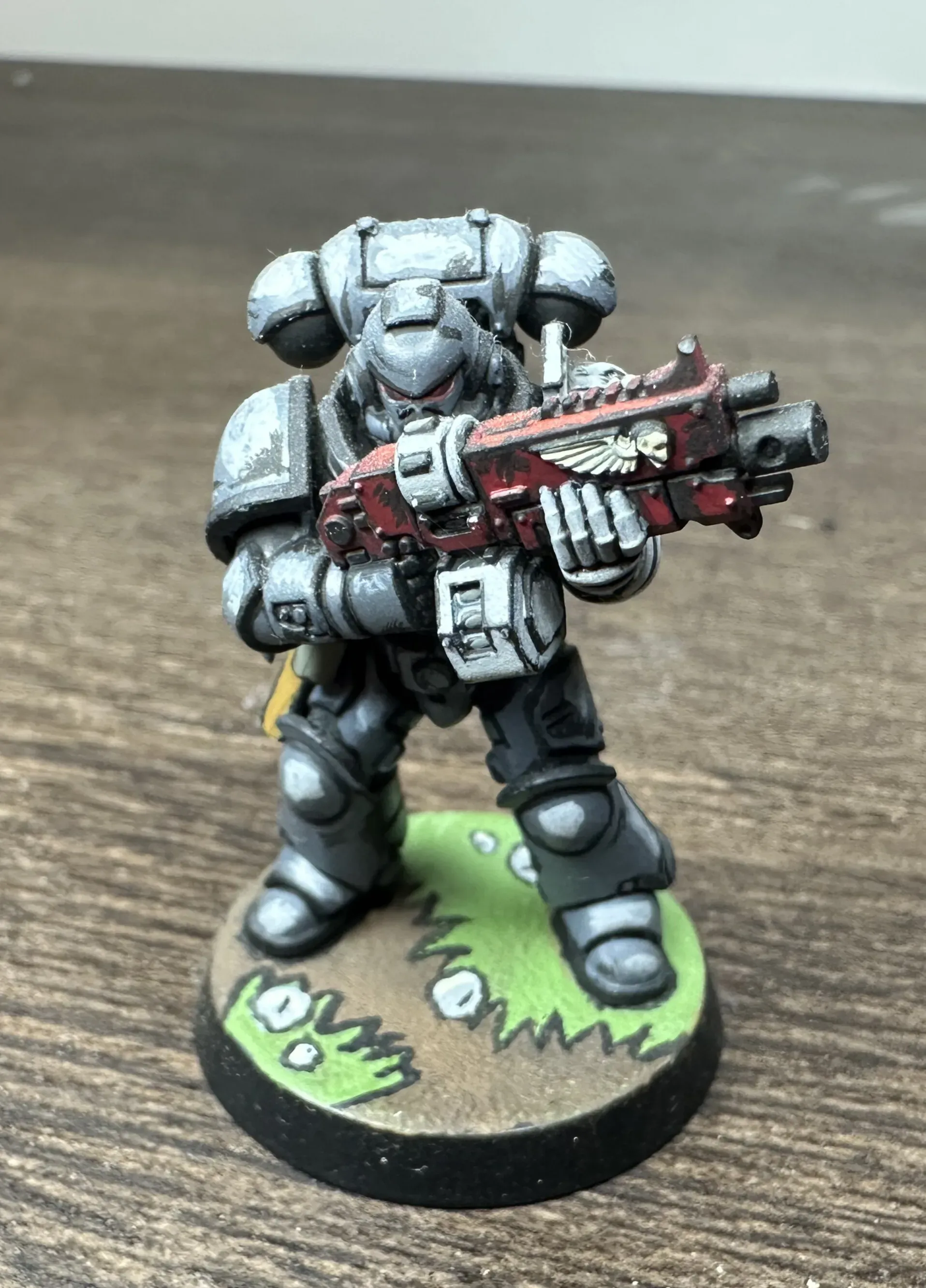Deathwatch space marine with silver armor and red bolter on comic book grass base