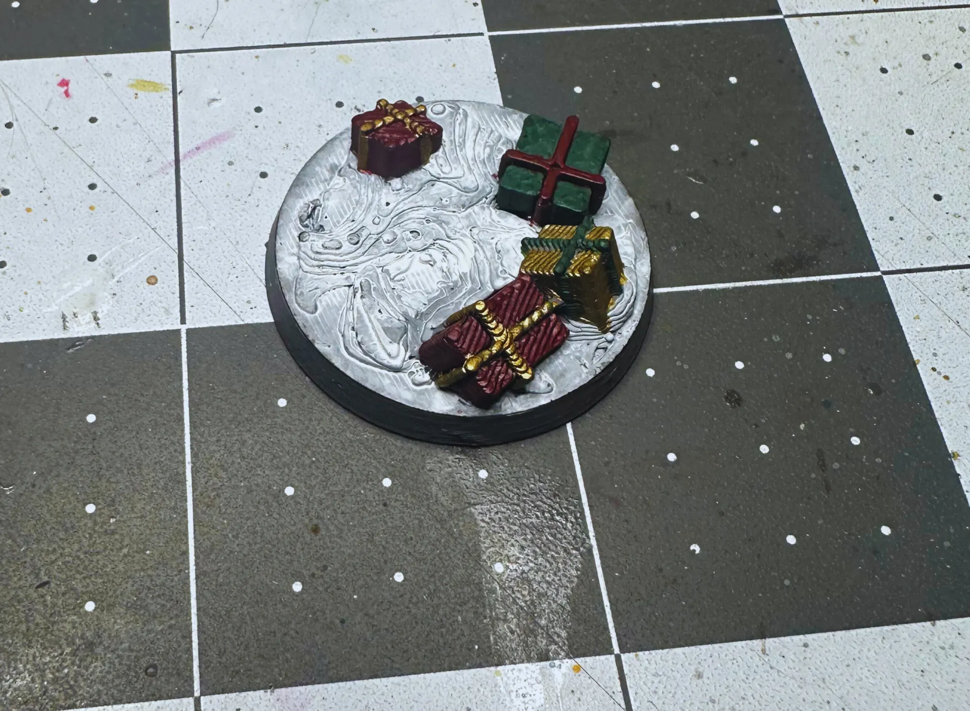 Closeup of Christmas base with painted presents in red, green, and gold